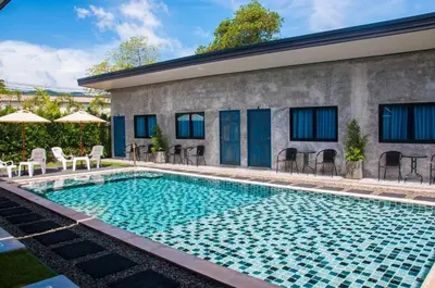 a swimming pool with chairs and a building at Ongsa House in Bang Tao Beach