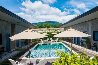 a swimming pool with two umbrellas and chairs at Ongsa House in Bang Tao Beach