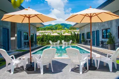 a group of chairs and umbrellas next to a pool at Ongsa House in Bang Tao Beach