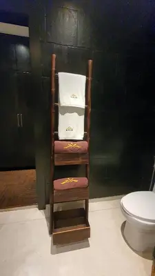 a wooden chair with towels on it next to a toilet at By The Lake Villas in Nai Harn Beach