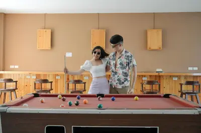 a man and woman standing next to a pool table at Nonnee Hotel Kata Beach Phuket in Kata Beach