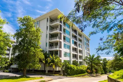 an apartment building with trees in front of it at The Palm at Veloche Group by Lofty in Karon Beach