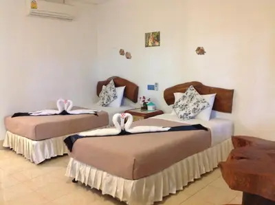 a bedroom with two beds with towels on them at Ruan Mai San Ngam Resort - SHA Plus in Nai Yang Beach