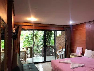 a bedroom with a bed and a view of a patio at Ruan Mai San Ngam Resort - SHA Plus in Nai Yang Beach