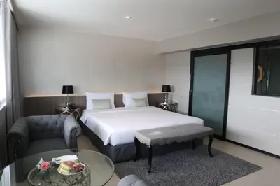 a bedroom with a bed and a couch and a table at Pearl Hotel Phuket in Phuket Town