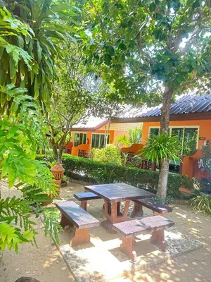 a picnic table with two benches in a garden at Baan Vanida Garden Resort in Karon Beach