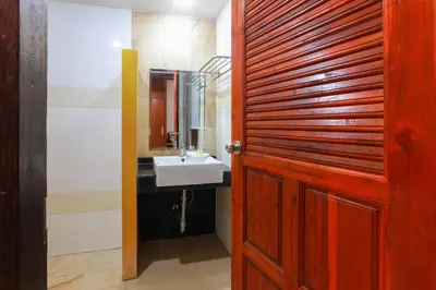 a bathroom with a sink and a wooden door at Baan Vanida Garden Resort in Karon Beach