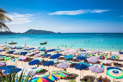 a beach with many umbrellas and people in the water at The Deck Patong by VIP in Patong Beach