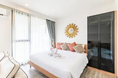 a bedroom with a white bed with a large window at The Deck Patong by VIP in Patong Beach