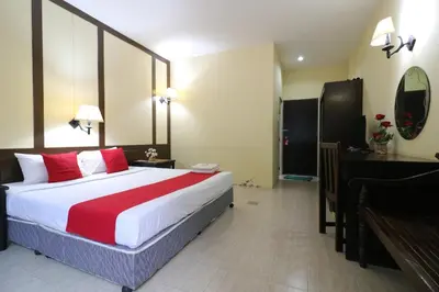 a hotel room with a large bed with red pillows at Baan Nat The Village in Phuket Town