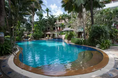 a swimming pool at a resort with palm trees at The Viridian Resort Patong in Patong Beach