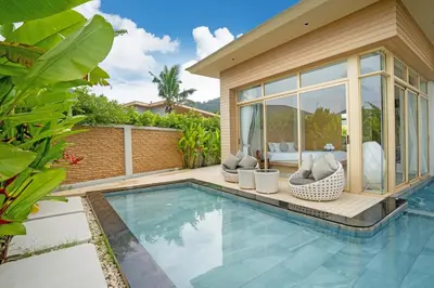 a swimming pool in front of a house at Himmapana Villas - SHA Extra Plus in Kamala Beach