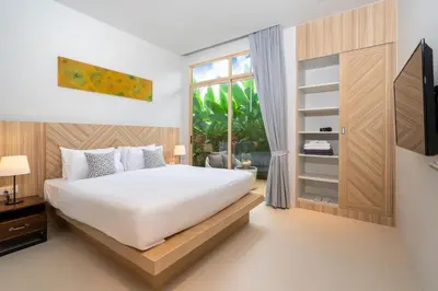a bedroom with a bed and a tv and a window at Himmapana Villas - SHA Extra Plus in Kamala Beach