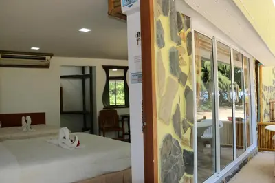 a room with two beds and a view of a patio at Ruan Mai Naiyang Beach Resort in Nai Yang Beach