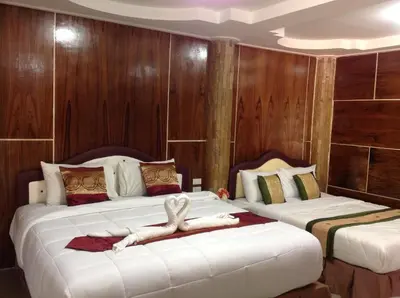 two beds in a hotel room with a person laying on them at Ruan Mai Naiyang Beach Resort in Nai Yang Beach