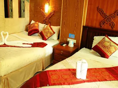 a hotel room with two beds and a night stand at Ruan Mai Naiyang Beach Resort in Nai Yang Beach