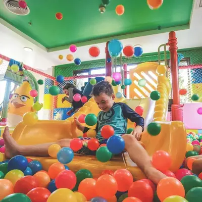 a young boy sitting on a slide in a playground at Radisson Resort and Suites Phuket in Kamala Beach