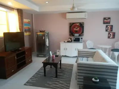 a living room with a couch and a tv at Résidence Chez Nous Phuket in Rawai Beach