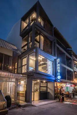 a building with a blue sign on the side of it at Sleep Box Patong Hostel in Patong Beach