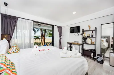 a bedroom with a large white bed with a window at Thai Kamala Beach Front in Kamala Beach