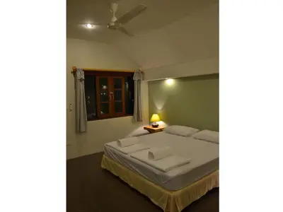 a bedroom with a large bed with a ceiling fan at Phuket Campground in Mai Khao Beach