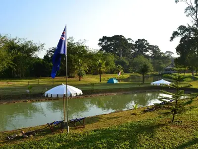 a flag in front of a pond with tents at Phuket Campground in Mai Khao Beach