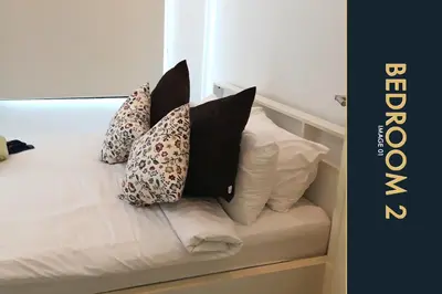 a bed with four pillows sitting on it at 3 BR Stylish Condo with Private Rooftop Pool in Kamala Beach