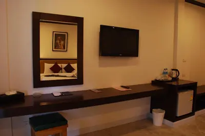 a room with a desk and a tv on the wall at Phukamala Suite in Kamala Beach