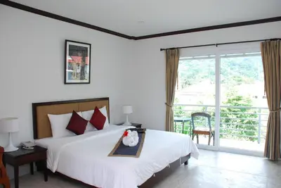 a bedroom with a large bed and a balcony at Phukamala Suite in Kamala Beach