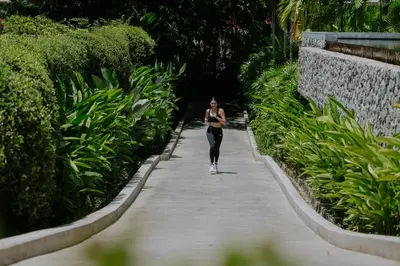 a woman walking down a walkway in a park at Amatara Welleisure Resort in Panwa Beach
