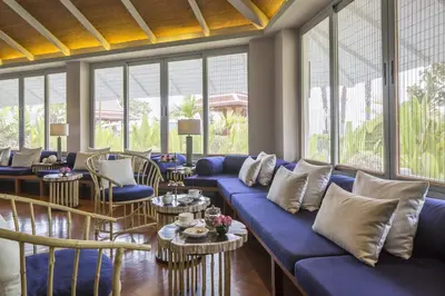 a living room with a blue couch and tables and windows at Amatara Welleisure Resort in Panwa Beach
