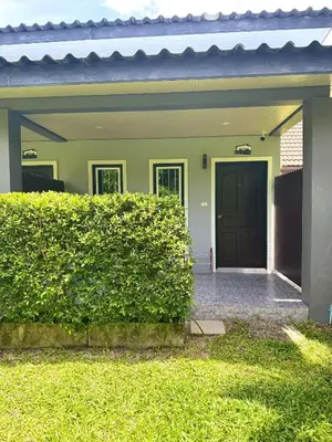 a house with a black door and a green hedge at Buncha Place in Bang Tao Beach