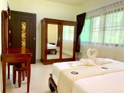 a bedroom with a bed and a desk and a mirror at Kannapat House in Ban Nong Thale
