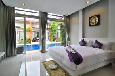 a bedroom with a large bed and a swimming pool at Phu NaNa Boutique Hotel - SHA Plus in Rawai Beach