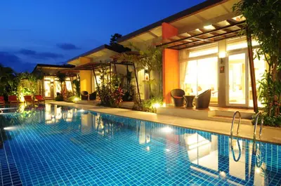a swimming pool in front of a house at night at Phu NaNa Boutique Hotel - SHA Plus in Rawai Beach
