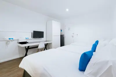 a bedroom with two beds and a desk with a computer at Blu Monkey Bed & Breakfast Phuket in Phuket Town