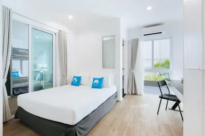 a bedroom with a white bed and a large window at Blu Monkey Bed & Breakfast Phuket in Phuket Town
