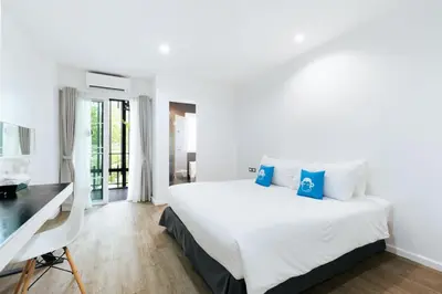 a white bedroom with a large bed and a desk at Blu Monkey Bed & Breakfast Phuket in Phuket Town