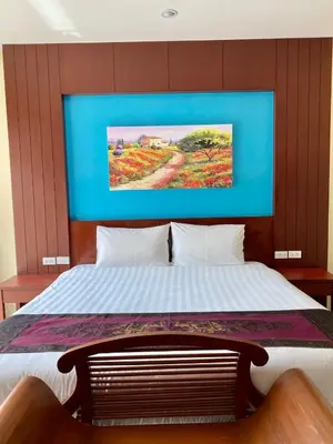 a bedroom with a bed with a painting on the wall at Baan Sudarat Hotel in Patong Beach