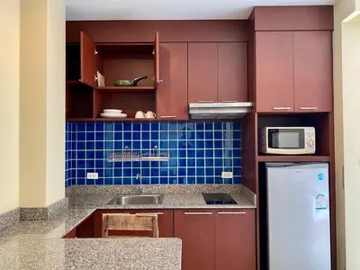 a kitchen with brown cabinets and a white refrigerator at Baan Sudarat Hotel in Patong Beach