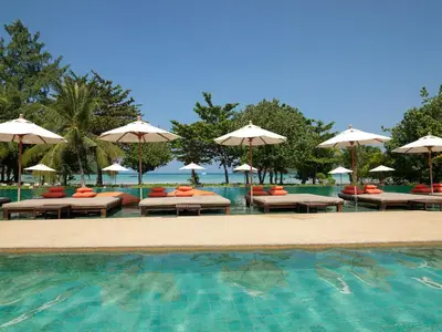 a swimming pool with tables and umbrellas and chairs at PP Charlie Beach Resort in Phi Phi Don