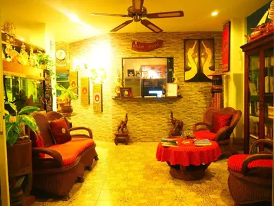 a living room with chairs and a table and a brick wall at Baan Rosa Bangtao Beach in Bang Tao Beach