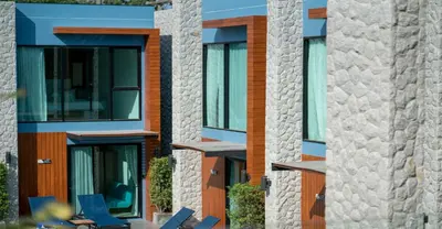 a row of buildings with windows and chairs at Peace Blue Naiharn Naturist Resort Phuket SHA Extra Plus in Rawai Beach