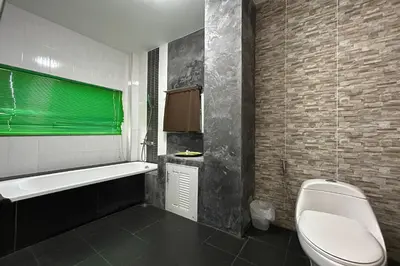 a bathroom with a tub and a toilet and a sink at Tann Anda Resort in Thalang