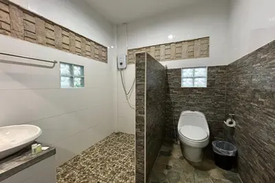 a bathroom with a toilet and a sink at Tann Anda Resort in Thalang