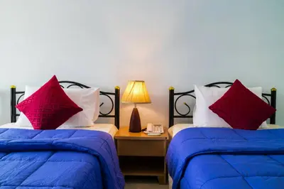 two beds with blue and red pillows in a room at Raya Rawai Place in Rawai Beach