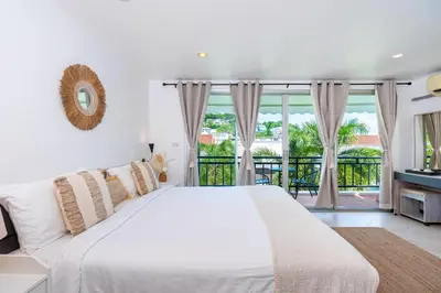 a white bedroom with a large bed and a balcony at Kata Station Boutique Hotel in Kata Beach
