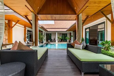 an outdoor patio with wicker furniture and a swimming pool at Champagne Villa Luxurious Tropical Pool Villa in Rawai Beach