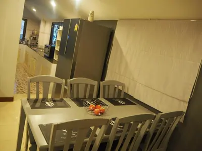 a kitchen with a table with chairs and a refrigerator at Beautiful 3 Bedroom Garden Villa in Chalong