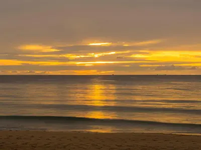 a sunset on the beach with the sun setting at Infinity Blue Phuket by Elite Havens in Natai Beach